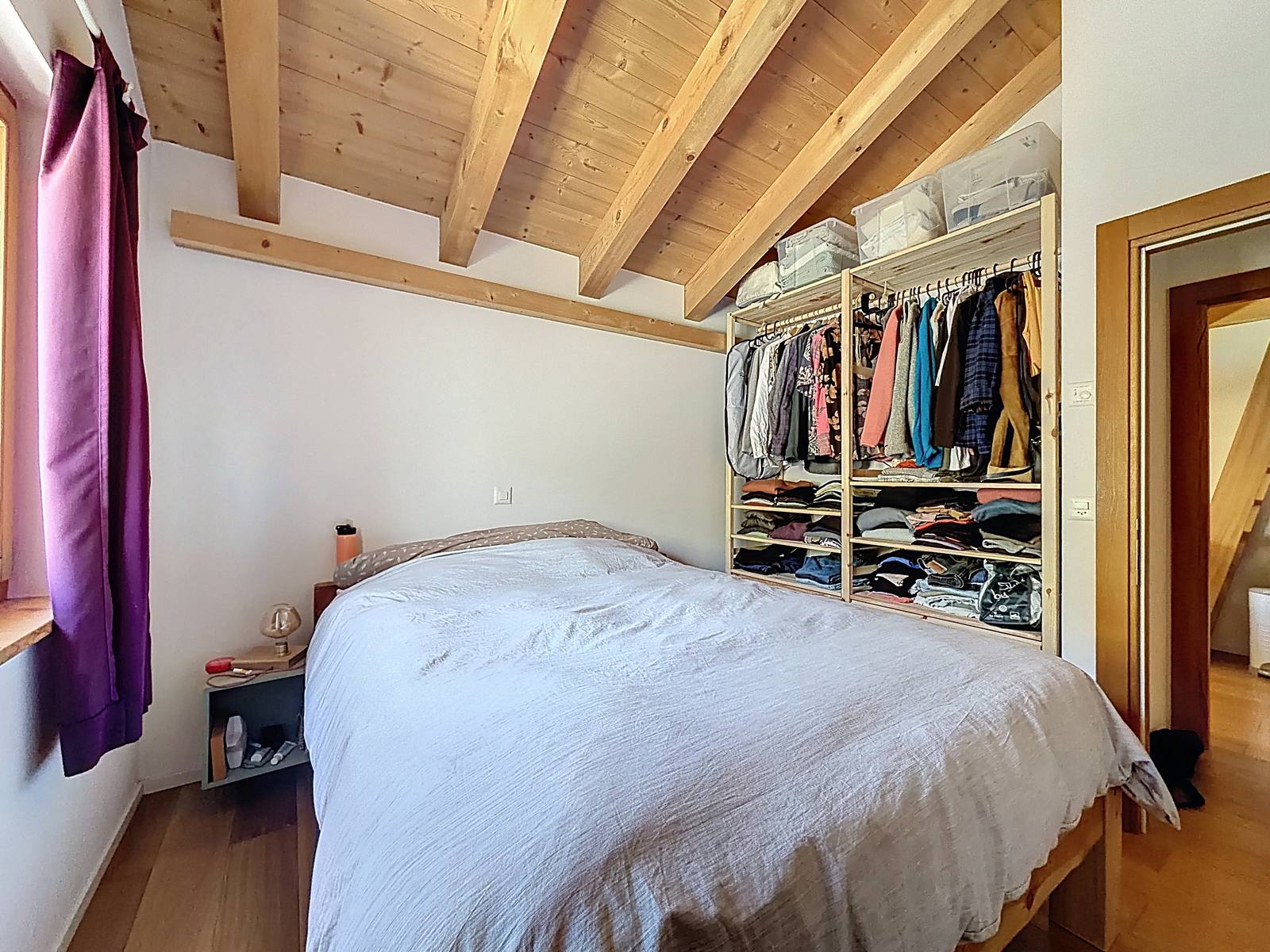 La chambre principale vue depuis l'autre angle, poutres apparentes au plafond.