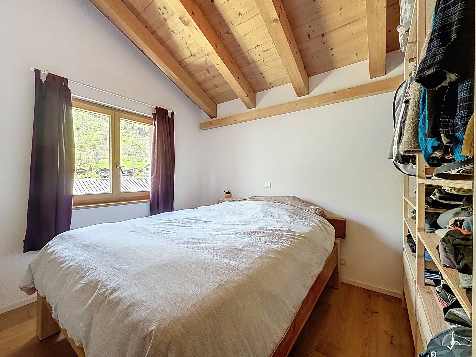 La chambre principale, lit double, dressing ouvert et fenêtre sur les montagnes.