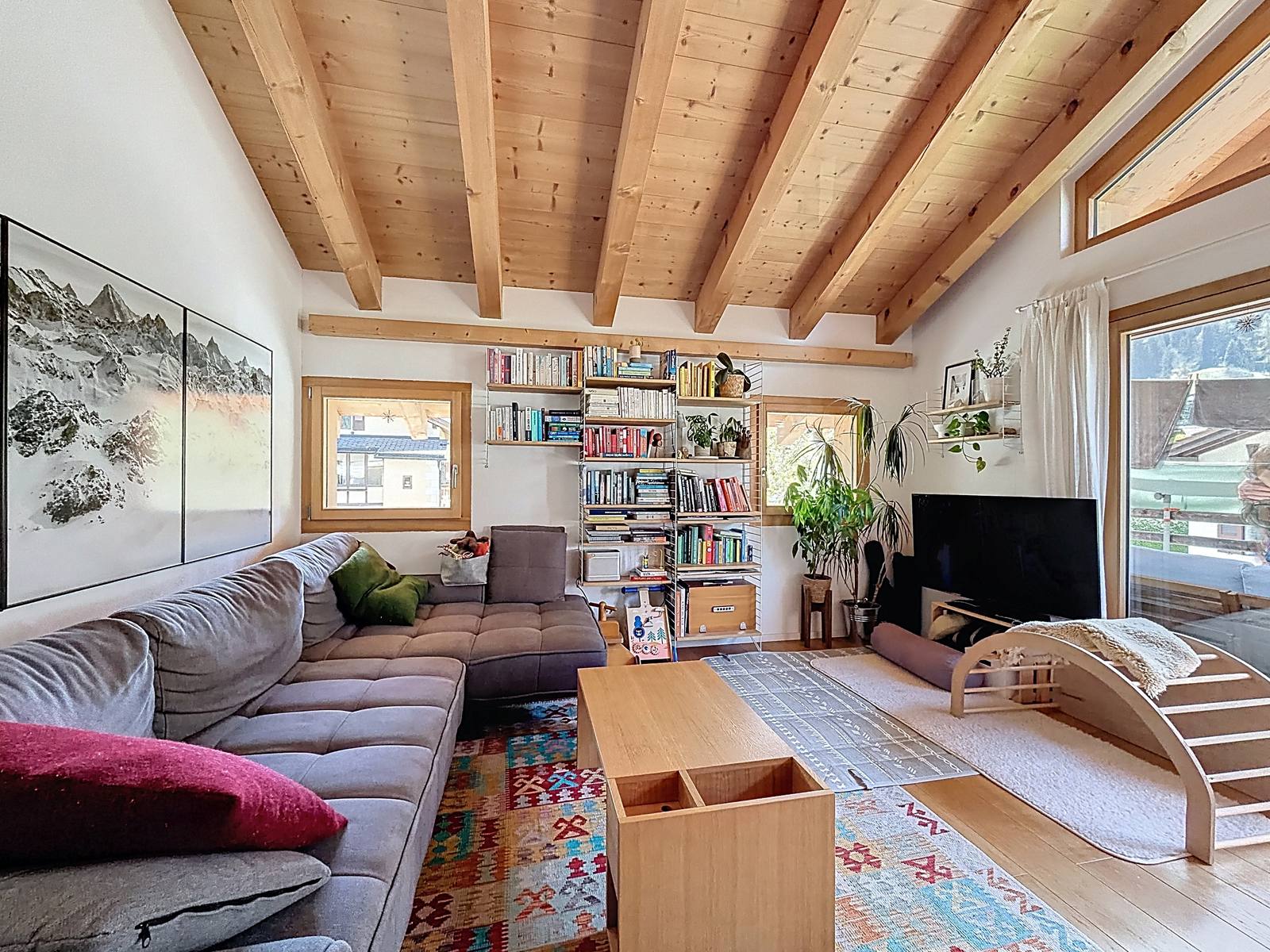 Coin salon avec bibliothèque sur mesure et accès au balcon par la baie vitrée.